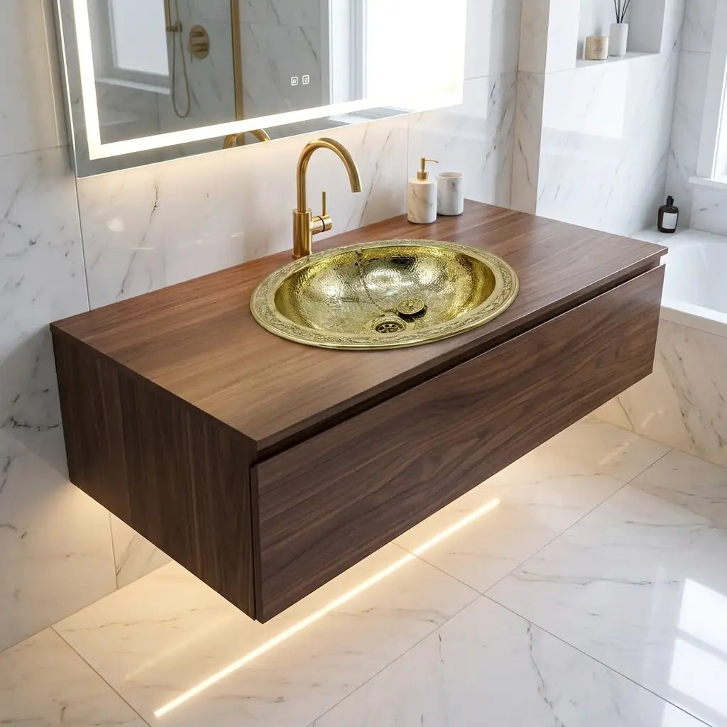 Hand-engraved oval brass drop-in sink with intricate Moroccan geometric patterns integrated into a floating walnut wood vanity cabinet