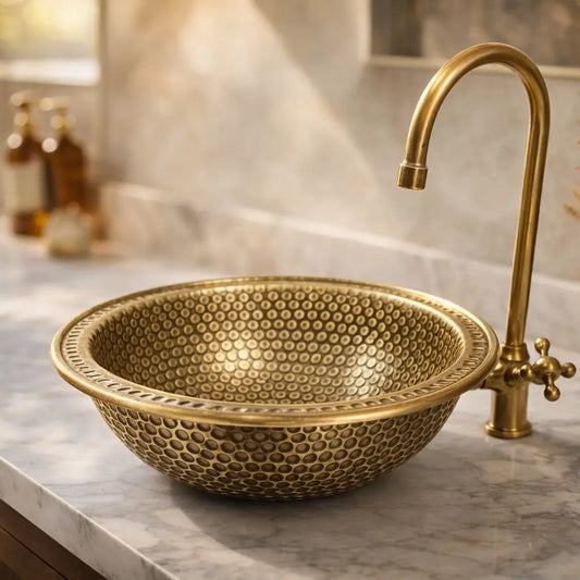 Luxury hand hammered brass bathroom sink installed on a clean white marble countertop in a modern bathroom.