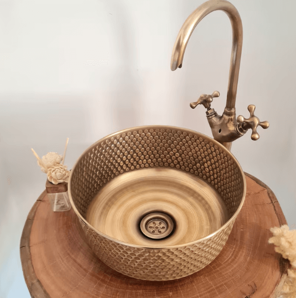 Luxury mid-century modern hammered brushed brass sink with stylish faucet on a wooden table.