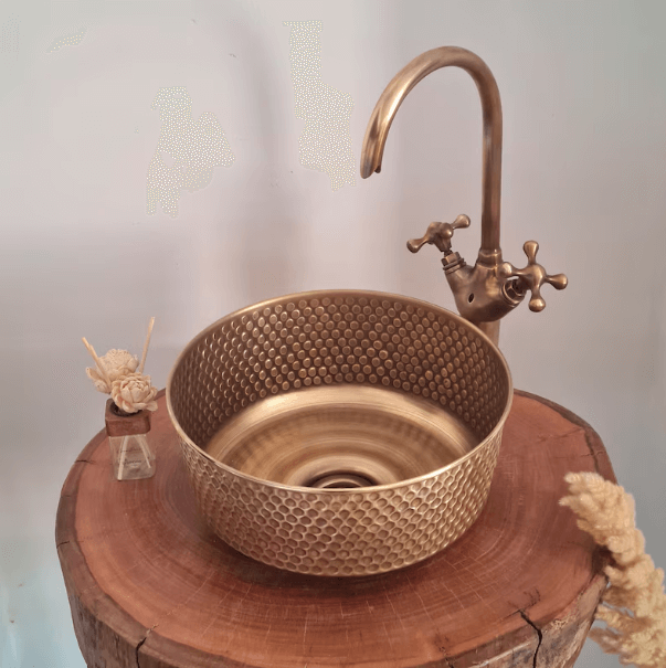 Mid-Century Modern hammered brushed brass sink and faucet on a wooden table, ideal for luxury bathroom upgrades.