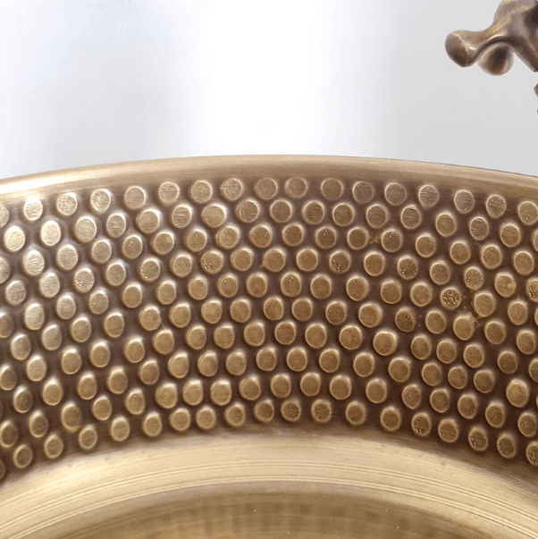 Close-up of a hammered brushed brass sink showcasing a dotted texture, perfect for luxury bathroom decor.
