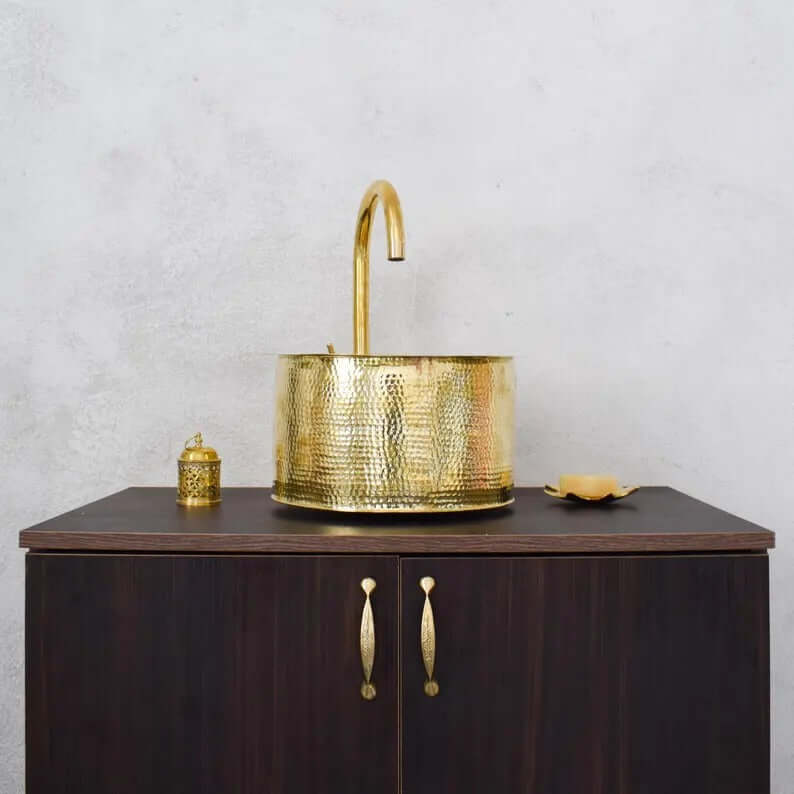 Handmade brass sink with a stylish faucet on a wooden cabinet, showcasing traditional Moroccan craftsmanship.