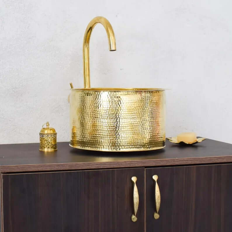 Handmade brass sink with hammered finish, styled with decorative accessories in a modern bathroom setting.