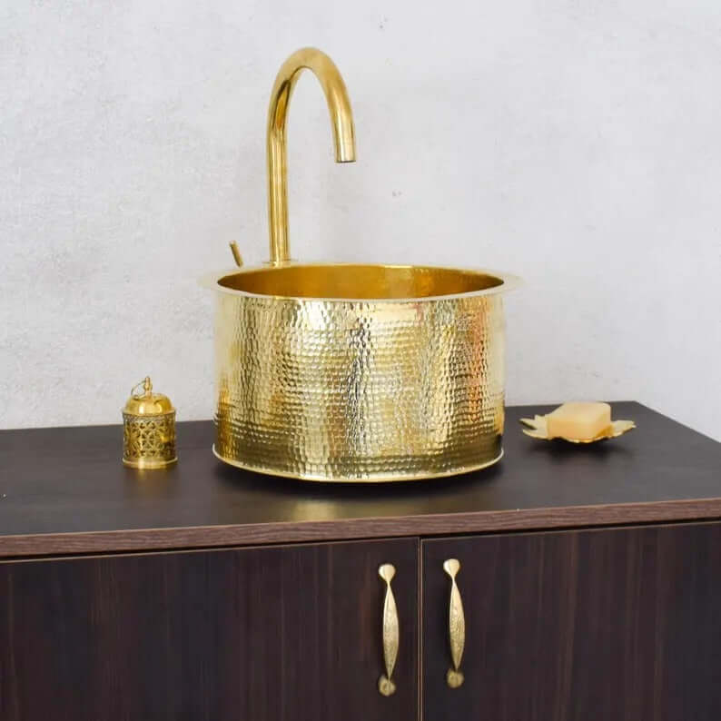 Handmade brass sink with elegant faucet on a wooden counter, featuring a traditional Moroccan design.