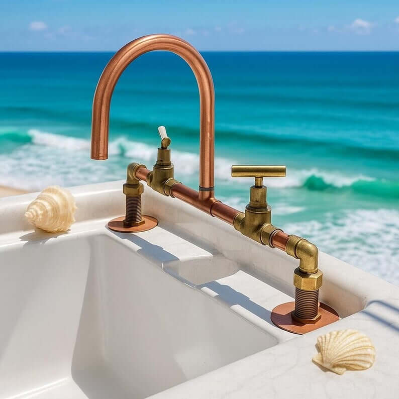 Handmade copper and brass faucet at an oceanfront sink, featuring rustic design and double handles.