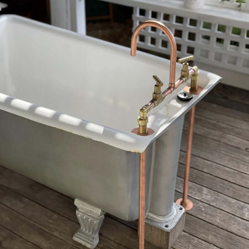 Handmade copper and brass faucet on vintage bathtub, showcasing rustic farmhouse design.