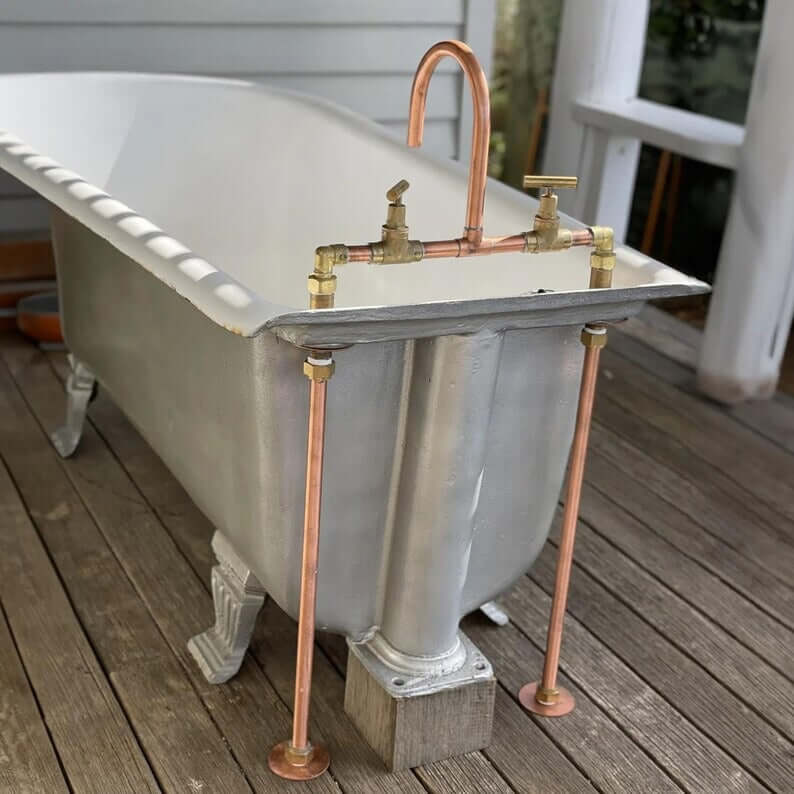 Handmade copper and brass faucet mounted on a vintage clawfoot bathtub, showcasing rustic farmhouse style.