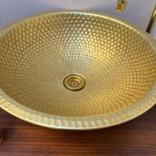 Handmade brass sink with a hammered finish, showcasing elegant texture perfect for bathroom or kitchen decor.