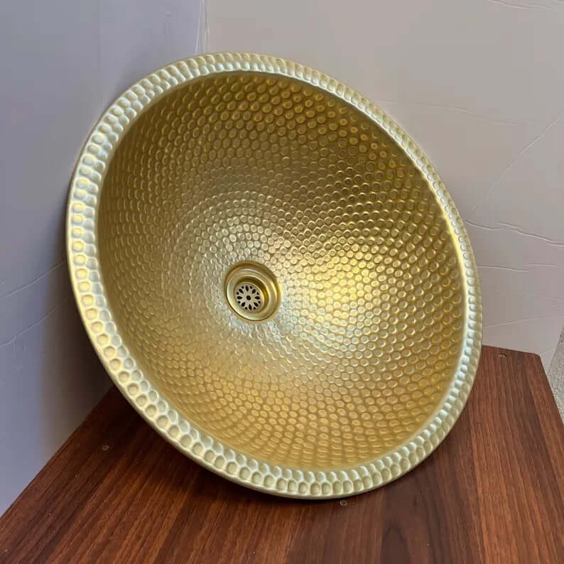 Handmade brass vessel sink with a polished hammered texture, perfect for bathroom decor.