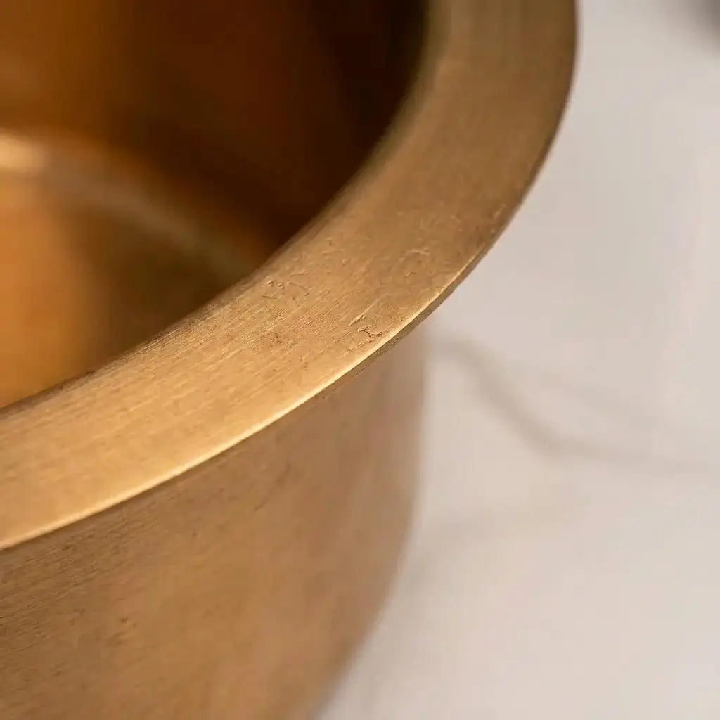 Close-up macro shot showcasing the high-quality brushed metal texture and durable thick rim of a handcrafted round brass luxury sink.