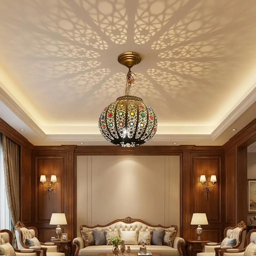 Circular brass pendant lamp with colorful glass in Moroccan style hanging in a luxury majlis room, casting oriental geometric light shadows across the white ceiling.