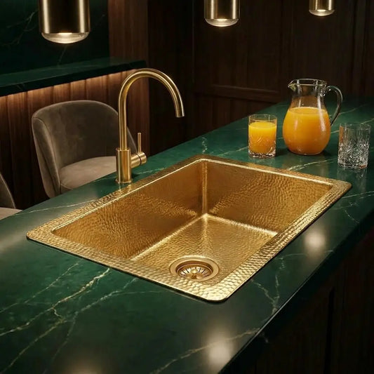30 inch rectangular hammered copper sink undermount installed on a luxury emerald green marble bar counter with a gold faucet and drinks