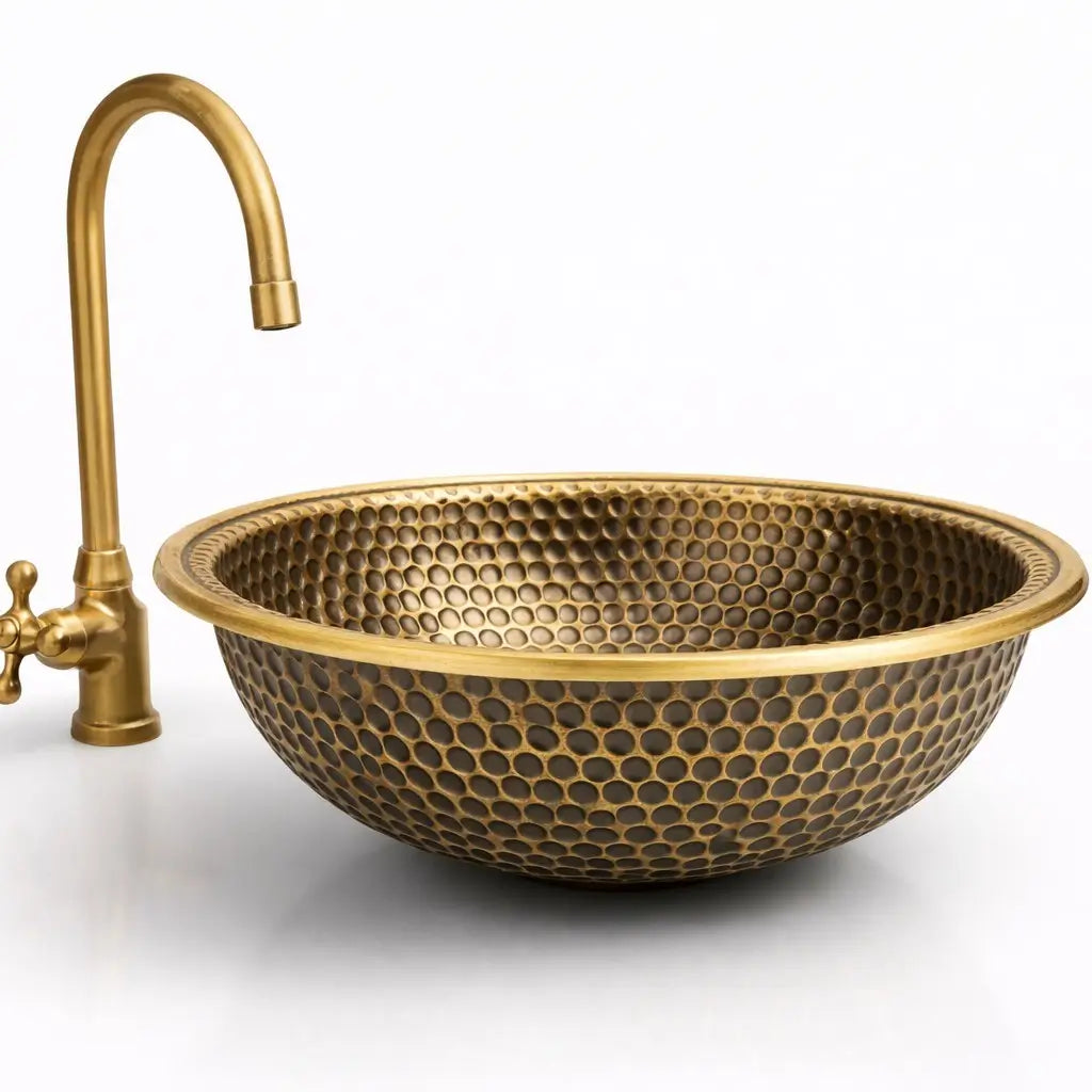 Hand hammered brushed brass vanity bowl with a left-side vintage faucet on a seamless white background.