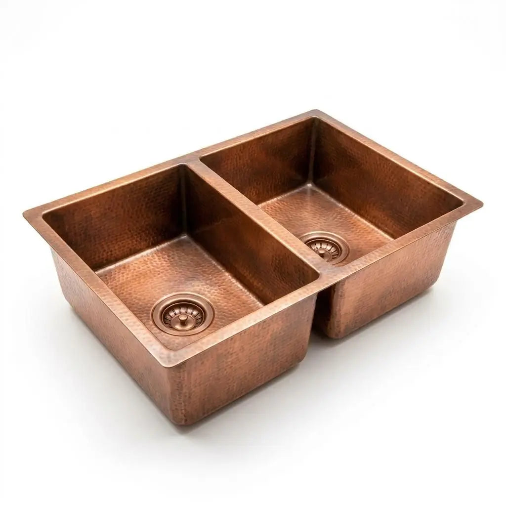 Handcrafted hammered copper double kitchen sink isolated on a clean white background, showcasing the dual basins and drains.
