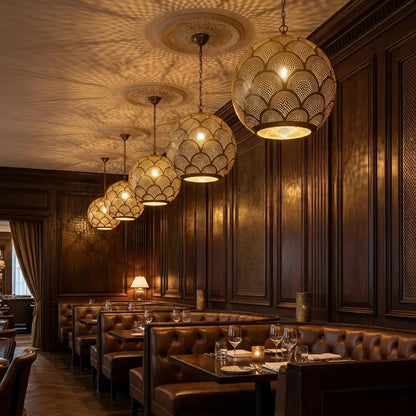 Artisan handmade brass pendant lights with Moroccan scale patterns illuminating a luxury restaurant dining area