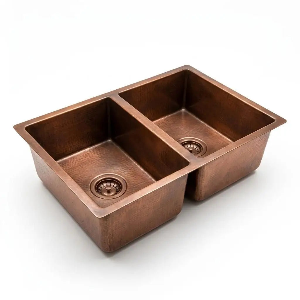 Studio shot of an uninstalled handmade double bowl copper kitchen sink with integrated drain strainers, isolated on a clean off-white background.