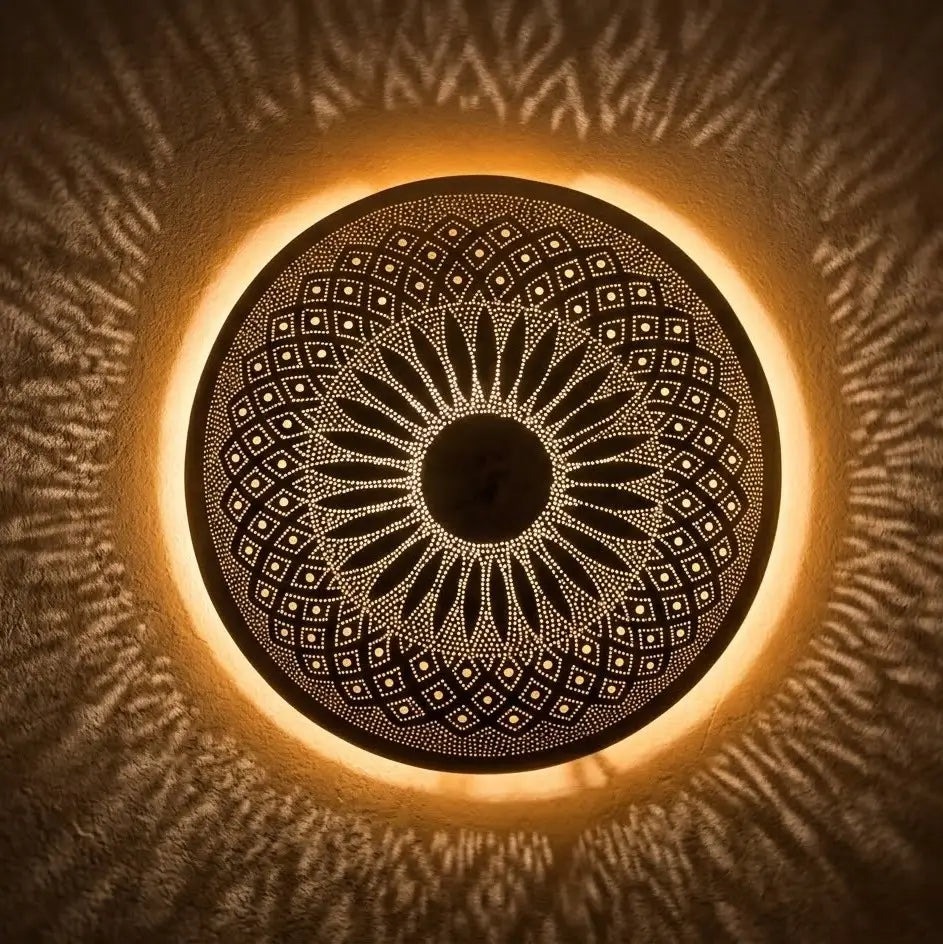 Handmade Moroccan brass wall sconce illuminated from behind, casting complex geometric and radial light shadow patterns.
