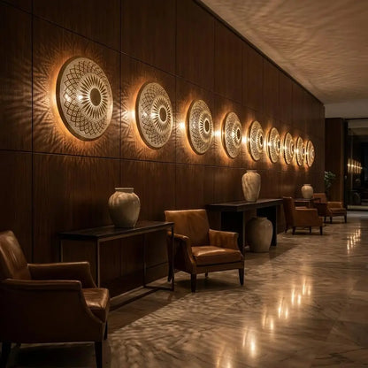 A row of handmade Moroccan brass wall sconces illuminating a luxury hotel lobby corridor with leather armchairs