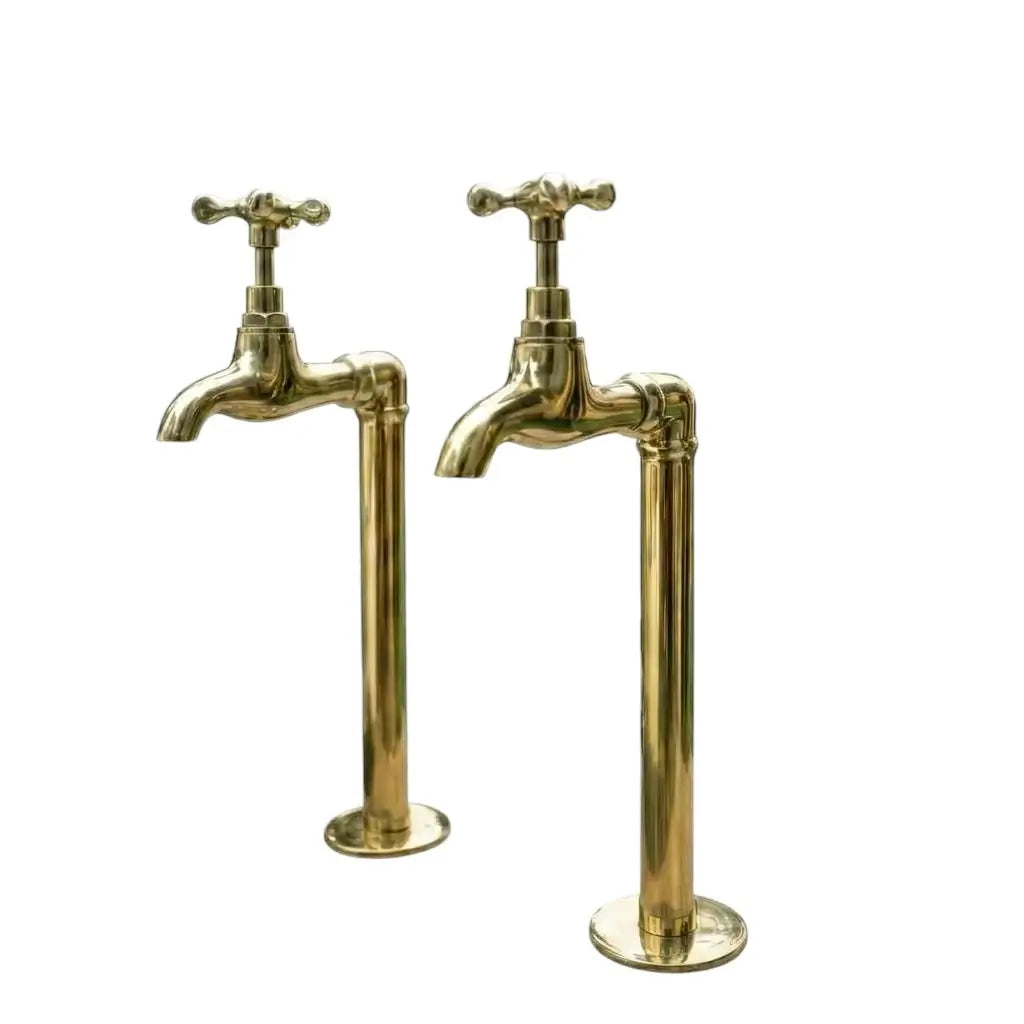 A pair of handmade unlacquered brass water dispenser faucets isolated on a solid white background
