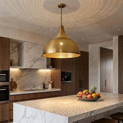 An illuminated Moroccan brass dome light hanging over a white marble kitchen island, casting intricate shadow patterns onto the ceiling of a modern contemporary home.