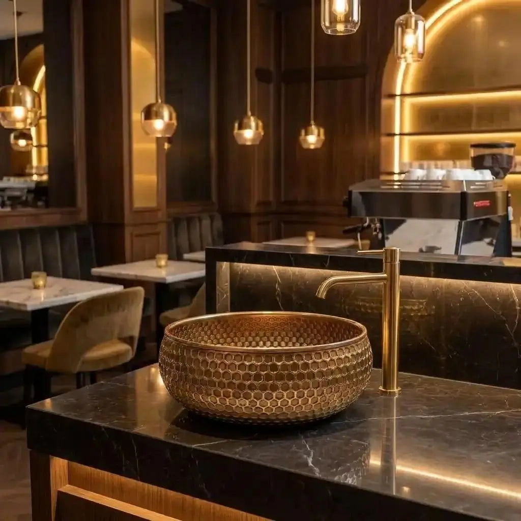 Mid-Century Modern Hammered Brushed Brass Sink with a honeycomb texture, luxury bathroom fixture installed on a black counter in a stylish cafe or restaurant lounge setting.