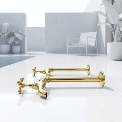 Full product display of two polished brass water filter cold taps with elegant cross handles lying on a clean white surface in a minimalist interior setting.