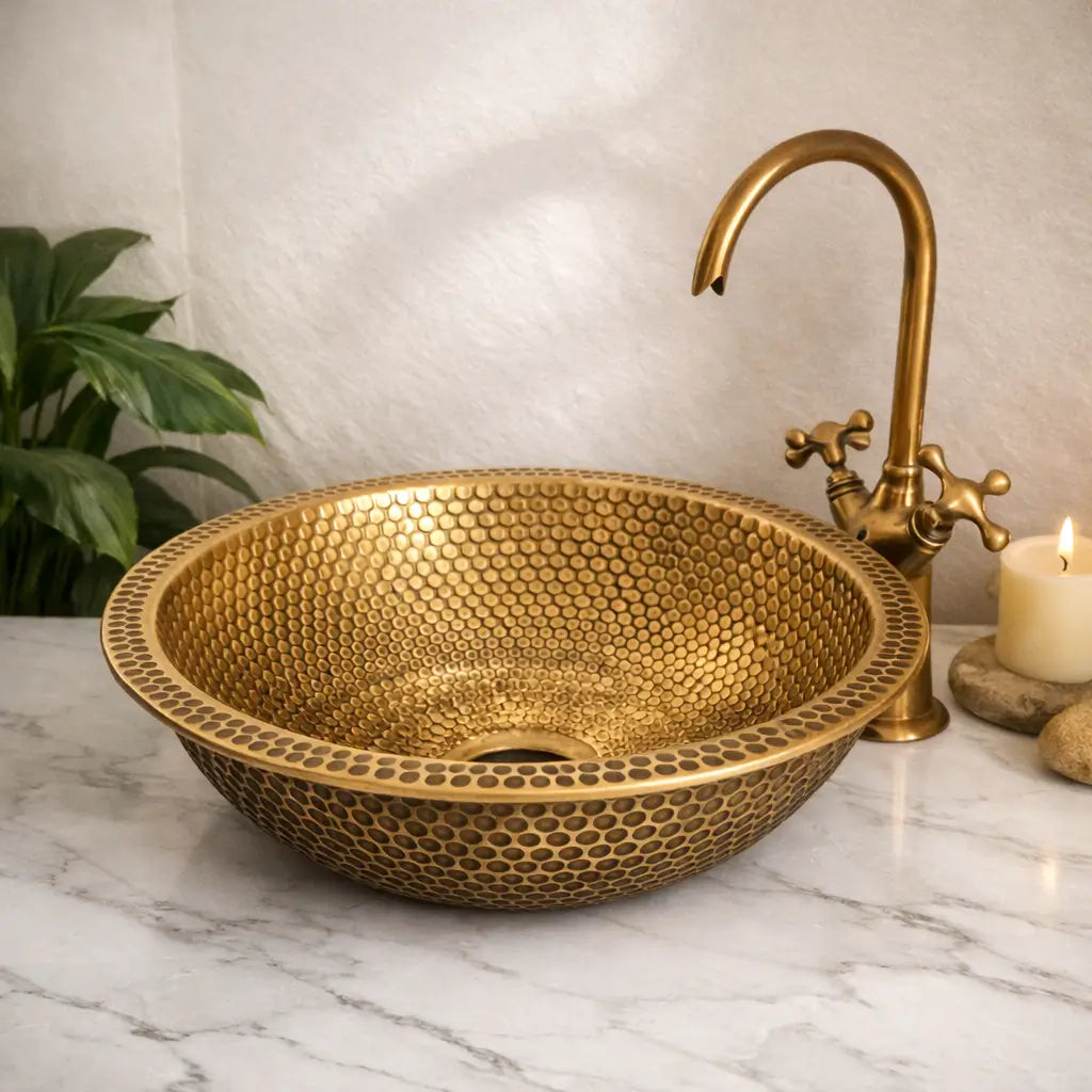 Premium custom made brushed brass bathroom sink with detailed honeycomb textures, set on a modern white marble vanity countertop under soft ambient light.