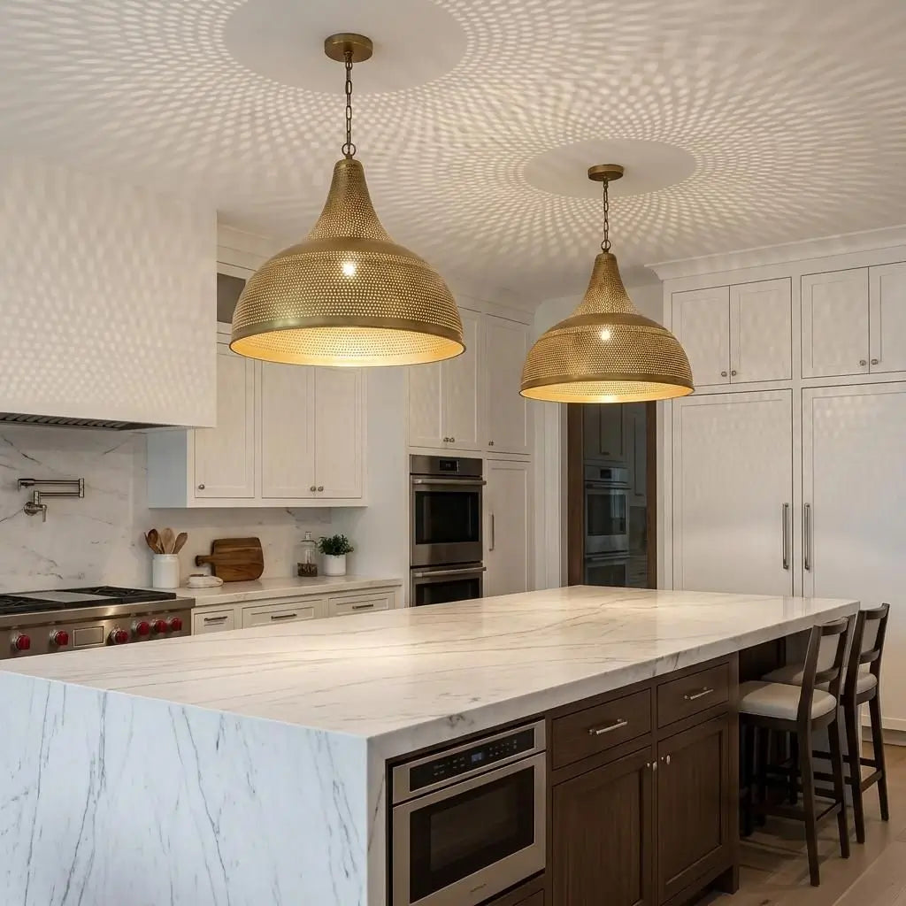 A pair of large Moroccan brass dome chandeliers suspended over a long white kitchen island, casting intricate starlight shadow patterns across the ceiling and bright contemporary cabinetry.