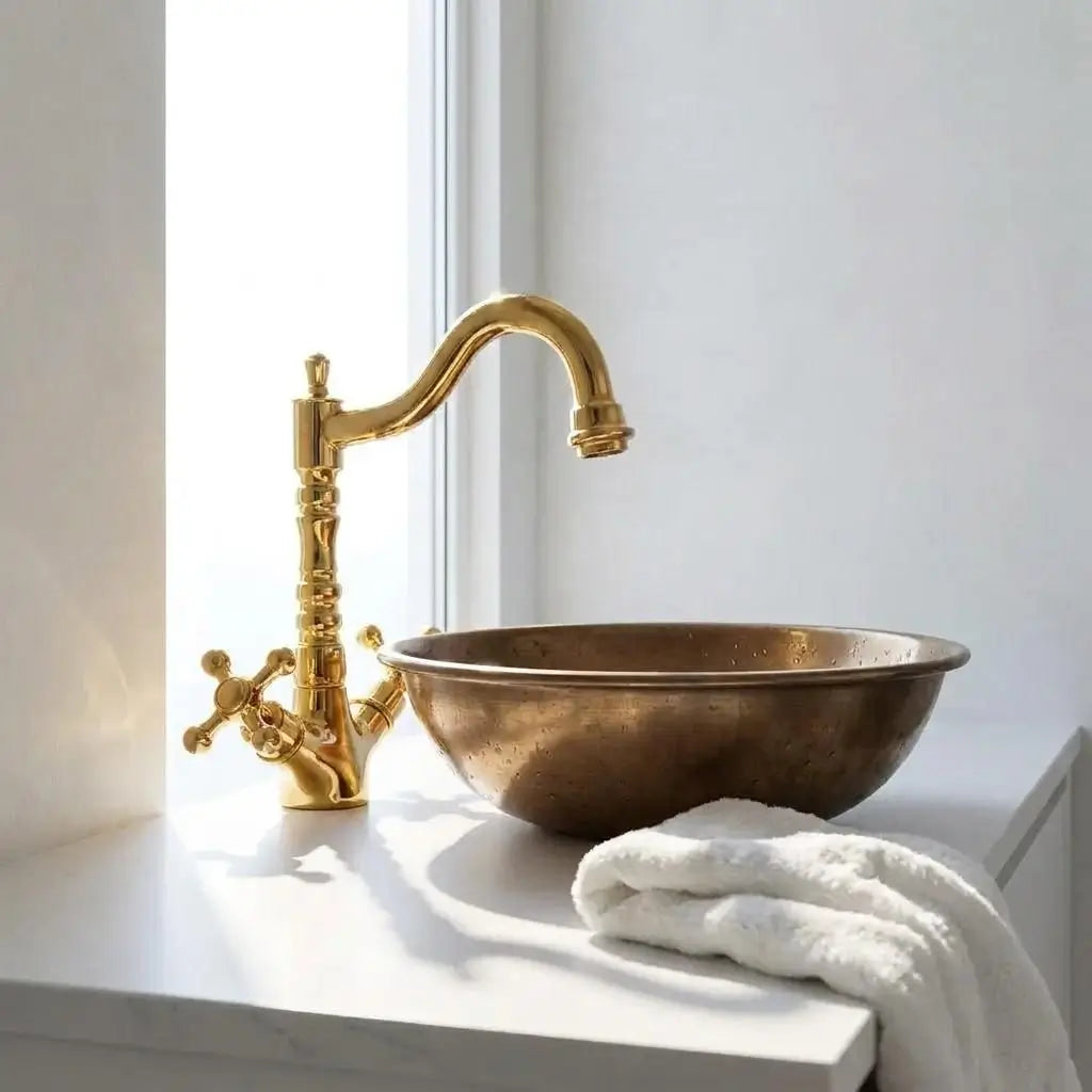 Moroccan brass vanity tap with a bronze sink bowl on a white countertop illuminated by bright natural window light.