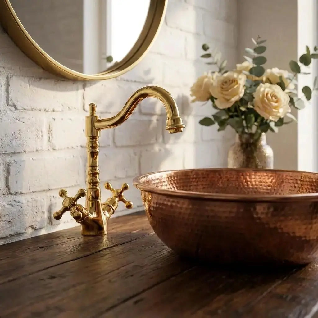 Moroccan brass vanity tap and hammered copper sink on a rustic wooden counter against a white brick wall.