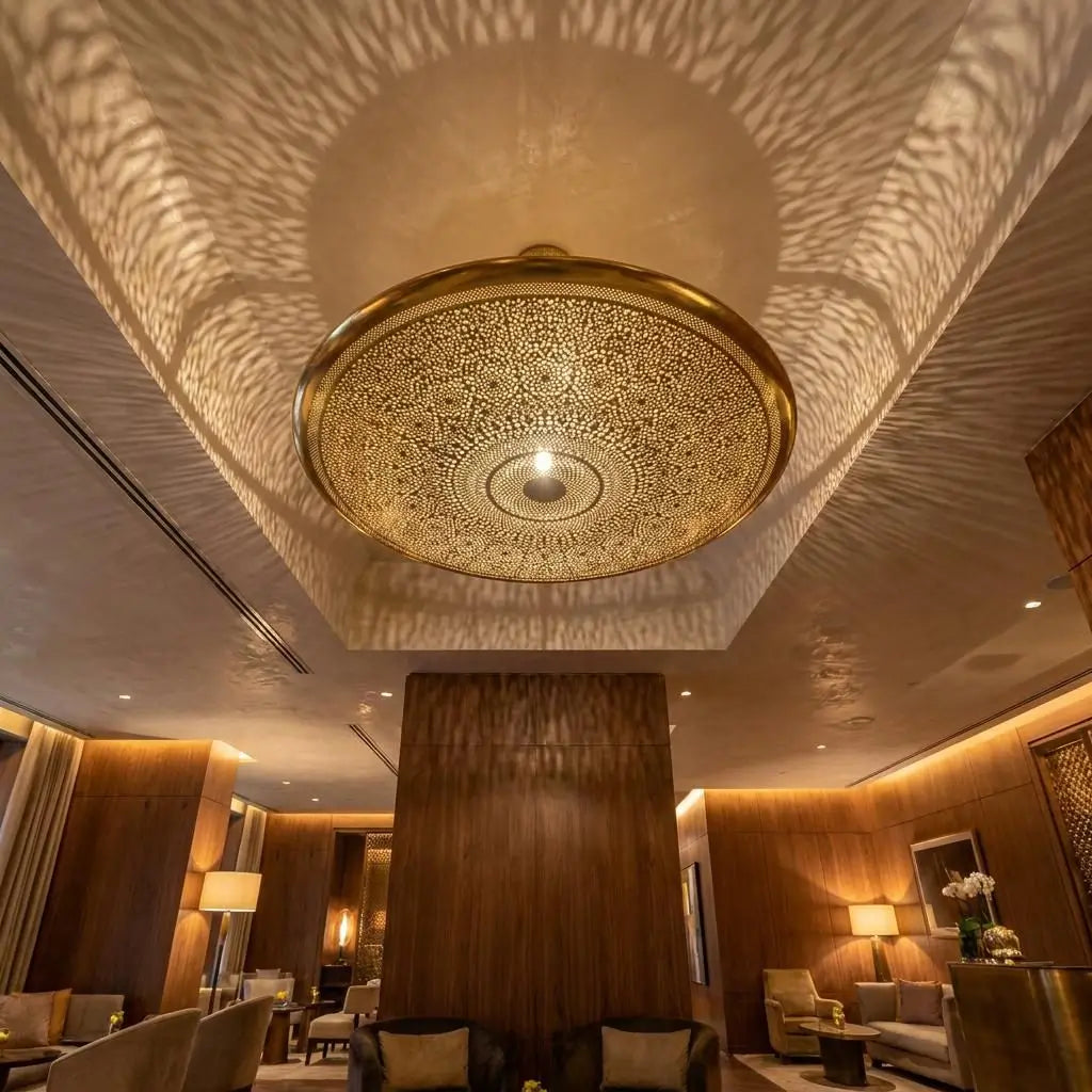 Moroccan dome brass ceiling lamp casting intricate wave patterns inside a recessed ceiling of a modern luxury lounge.