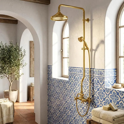 Moroccan unlacquered brass shower system with rain head installed on a wall featuring blue and white zellige patterned tiles next to arched windows.