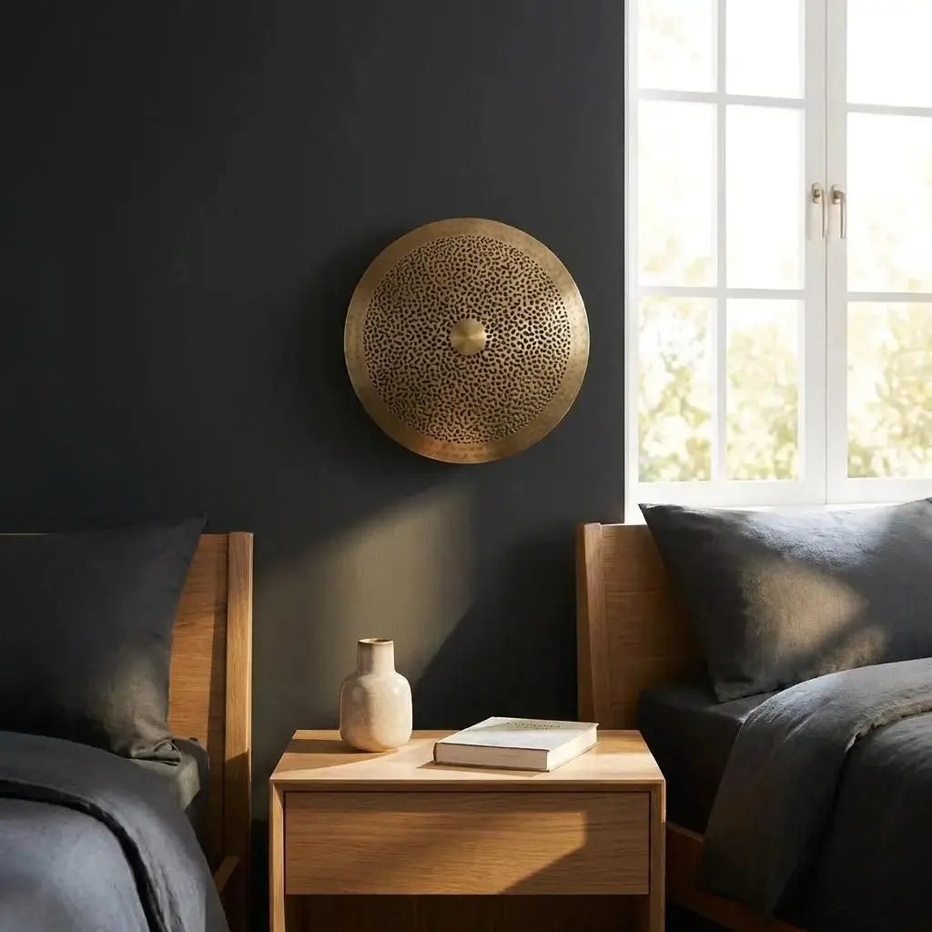 Moroccan wall light and handmade artisan brass lighting mounted on a dark accent wall between twin beds in a modern bedroom setting.