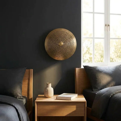 Moroccan wall light and handmade artisan brass lighting mounted on a dark accent wall between twin beds in a modern bedroom setting.