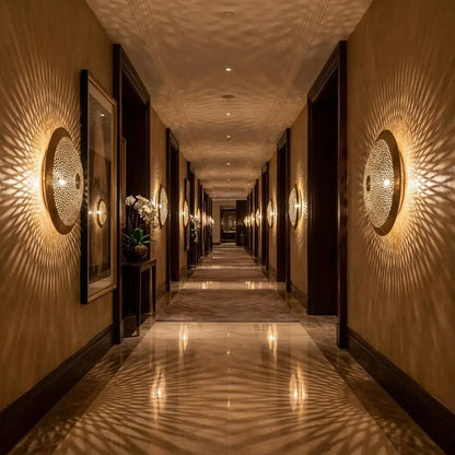Symmetrical Moroccan wall lights featuring handmade artisan brass lighting aligned along both sides of a long luxury hotel corridor with warm ambient reflections.