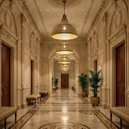 A long perspective of hanging Arabic brass dome ceiling lights decorating a palace-style corridor, shining over ornate marble stone walls, arched doorways, and tall golden planters.