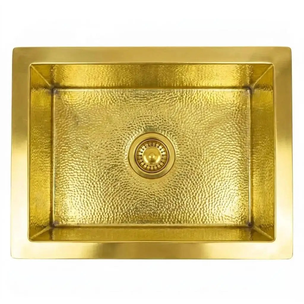 Top-down view of a rectangular handcrafted brass Moroccan sink with a hammered texture and centered brass drain strainer, isolated on a white background.