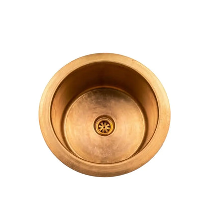Top view of a handcrafted round brass luxury sink with a central drain grid, isolated on a clean white background for e-commerce.