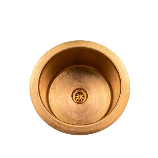 Top view of a handcrafted round brass luxury sink with a central drain grid, isolated on a clean white background for e-commerce.