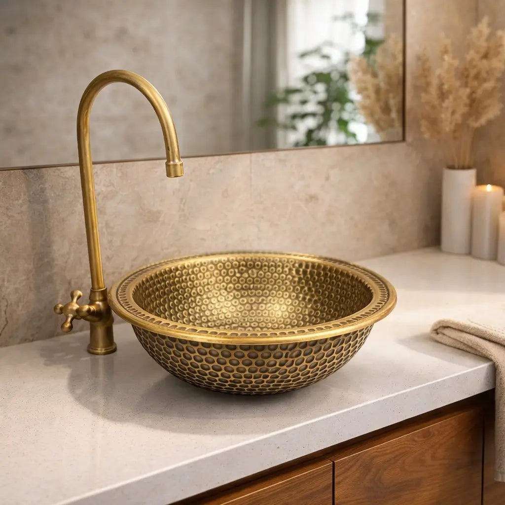 A round drop-in brass basin with a left-side faucet installed on a modern wooden vanity and quartz counter.
