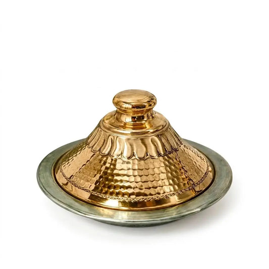 Handcrafted Moroccan copper tagine with a hammered metal conical lid and silver base tray isolated on a clean white background