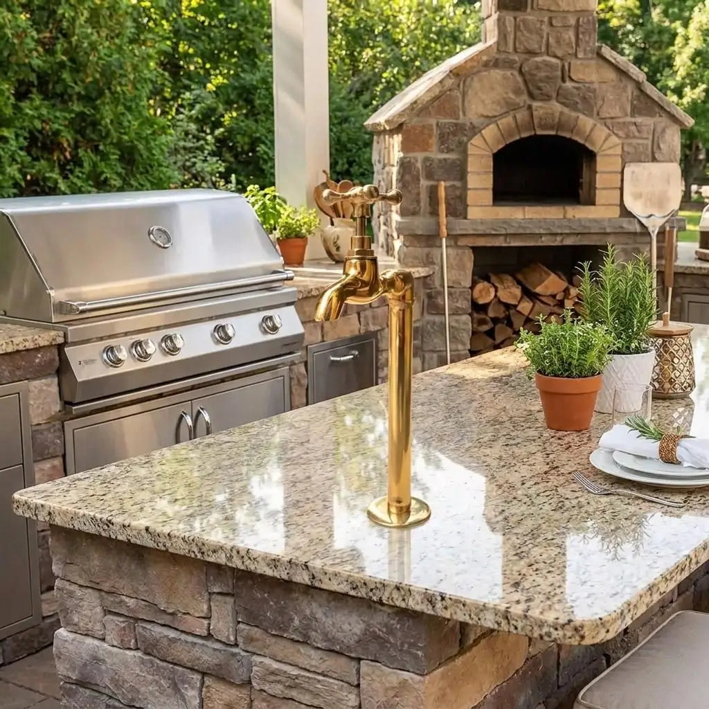 Premium unlacquered brass water dispenser faucet installed on a granite countertop in an outdoor kitchen next to a grill and pizza oven