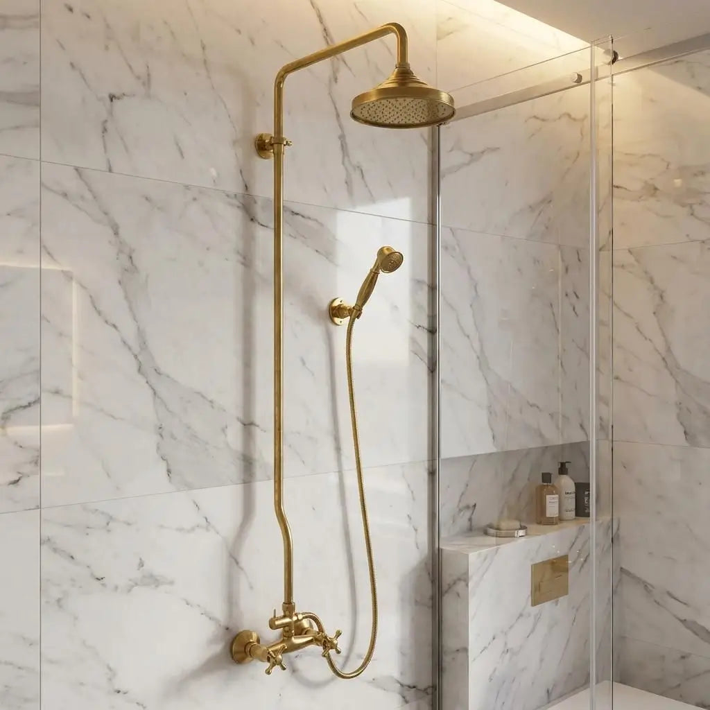 Unlacquered brass rain shower system with a Moroccan wall-mounted shower head and handheld unit, enclosed by a clear glass panel in a white marble bathroom.