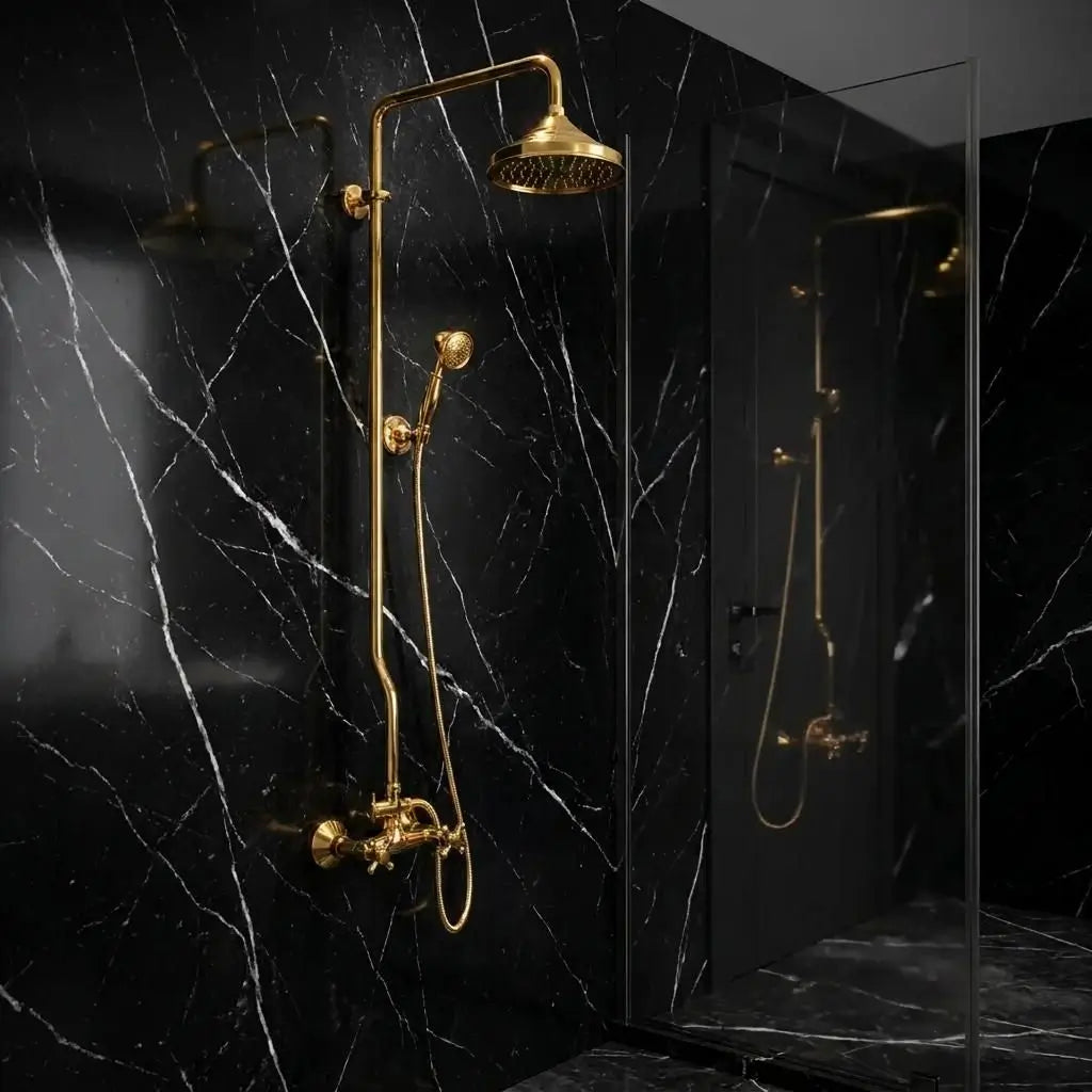 Unlacquered brass exposed pipe shower system with rainfall head and handheld sprayer installed on a luxury black marble wall with white veins.