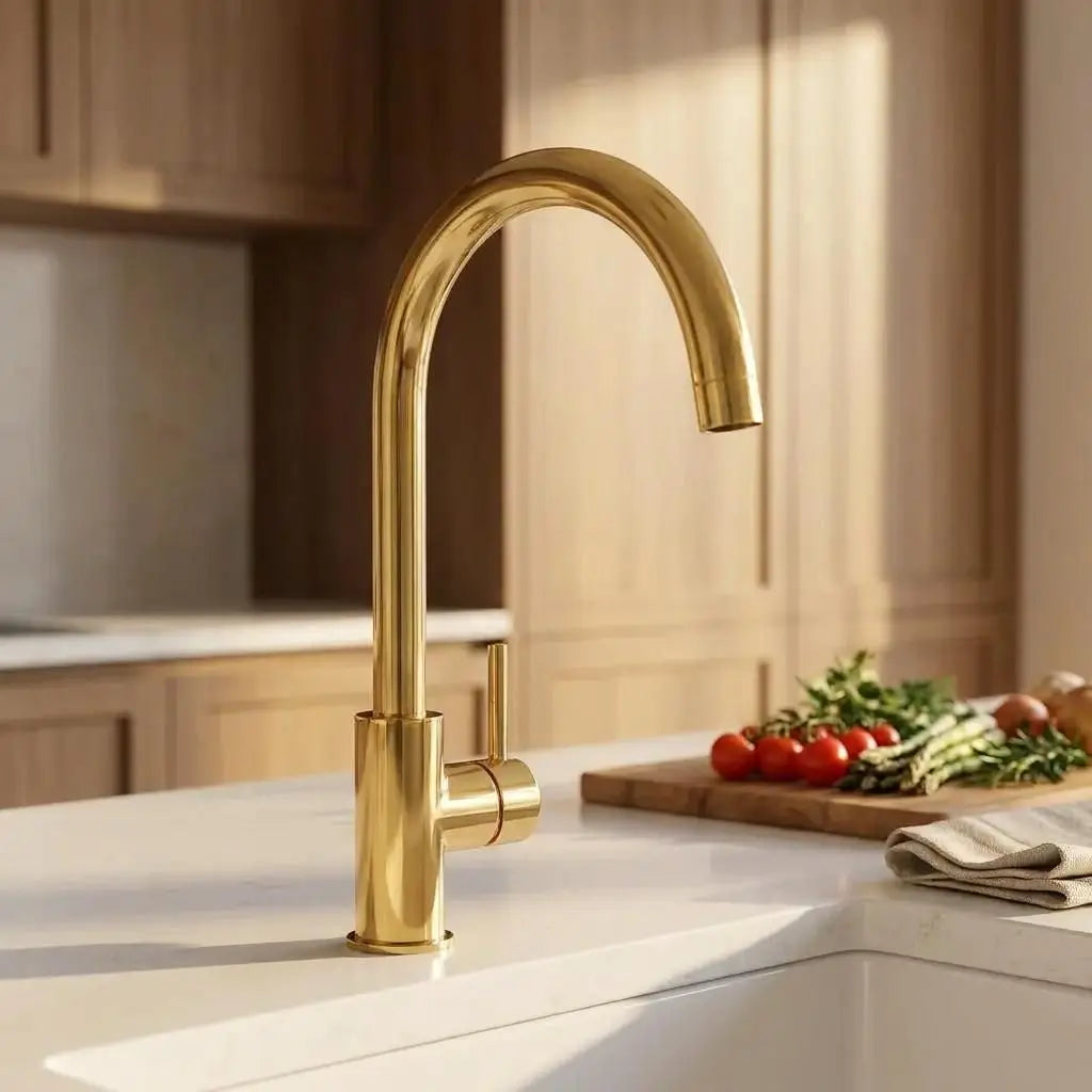 Close up back view of an unlacquered brass curved sink faucet on a white kitchen countertop.