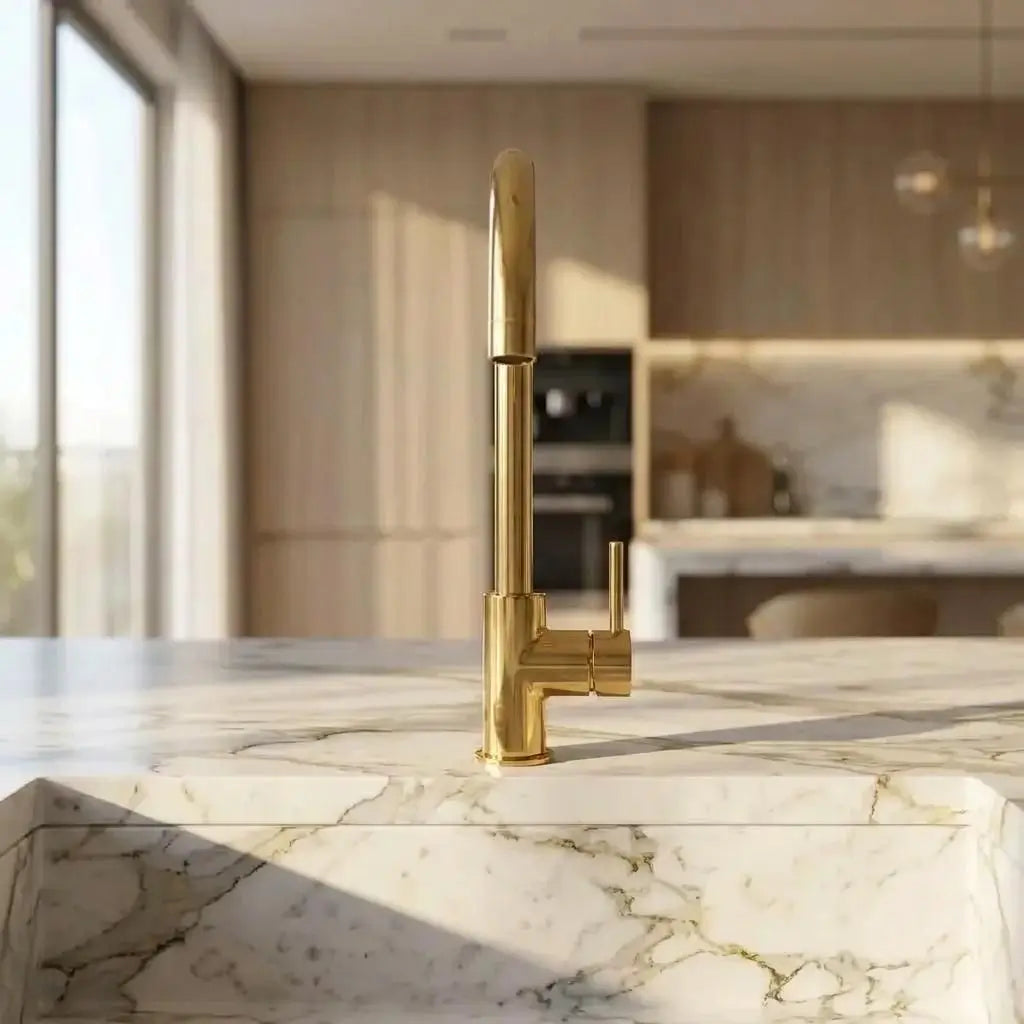 Front slim view of an unlacquered brass curved faucet installed on a white marble countertop.
